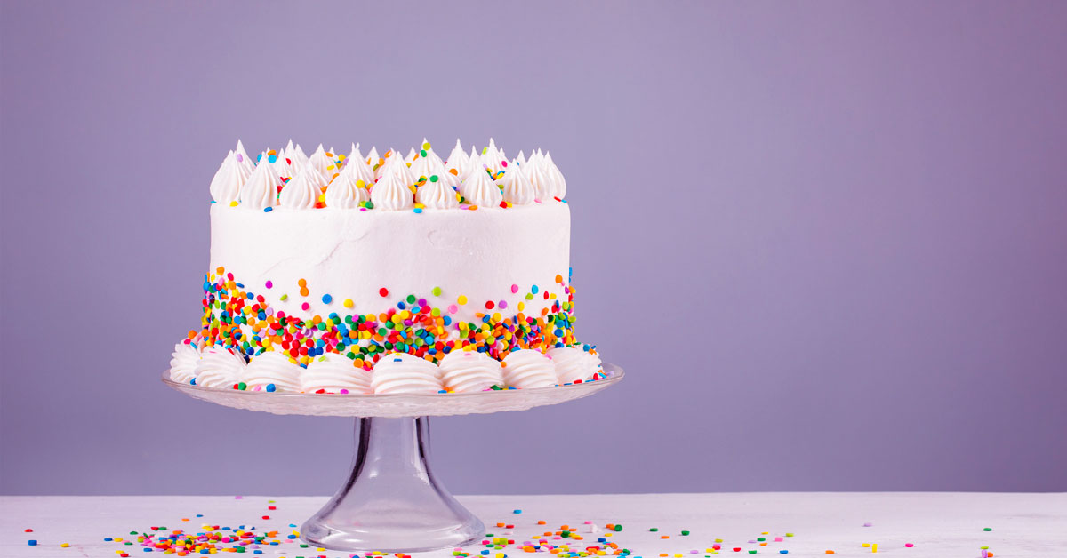 Torta ricoperta di panna e confetti colorati su alzatina